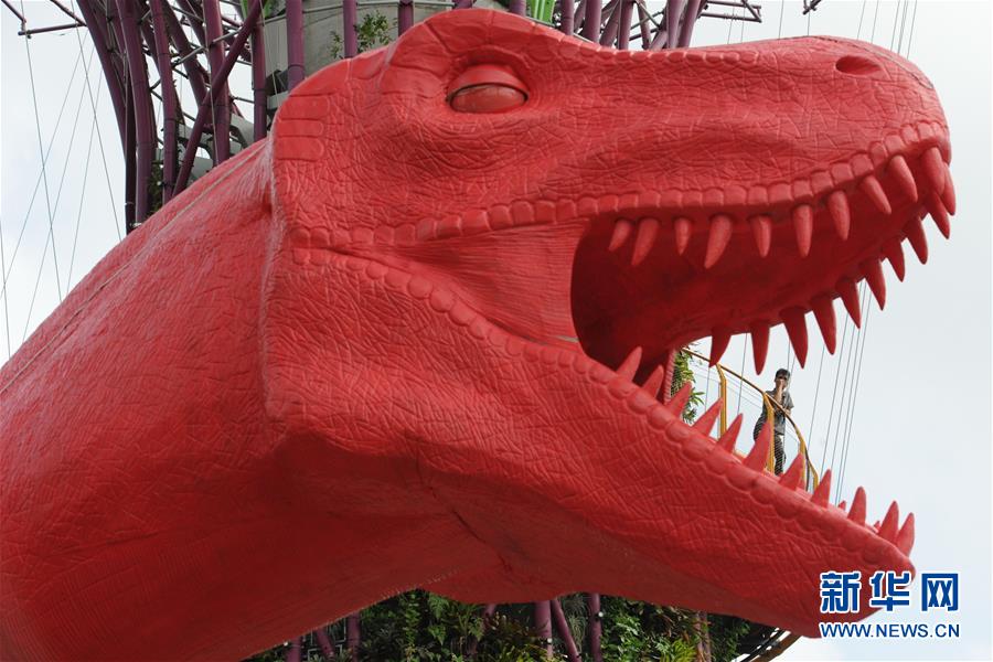 误入巨口 2月28日，一名游客在新加坡滨海湾花园擎天树林观赏恐龙模型。 （邓智炜/摄）